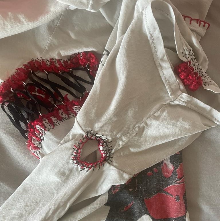 What an opportunity there is in knowing someone who could bore such grand holes in a shirt so that one day I could use it to practice new techniques. <br><br> On the left you can see the elastic corset, using yarn and embroidery thread to secure the metal loops and a black seed stitch to make sure it couldn't tear through the shirt. Similar methods were used in the hole below and on the sleeve you can see four tags also seen in traditional Nordic clothes, also secured to the shirt further with a black seed stitch pattern